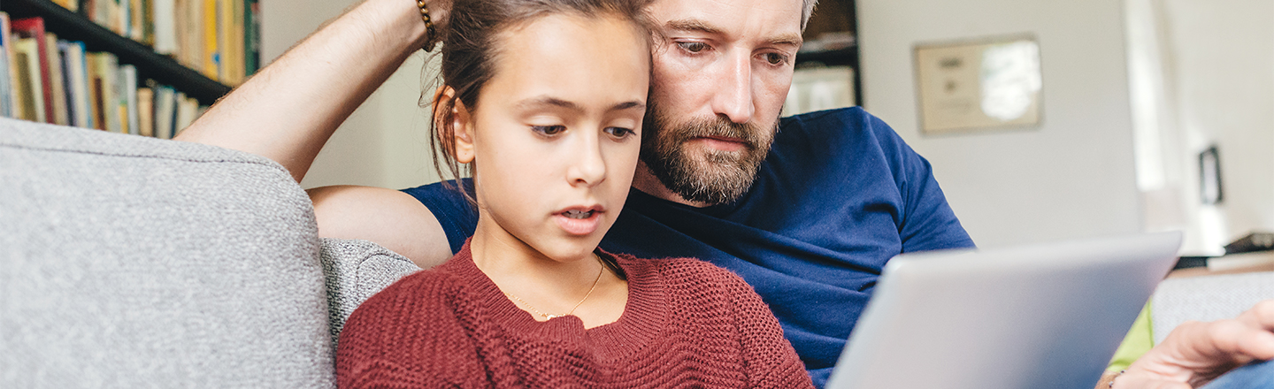 A father and his daughter looking at a PC
