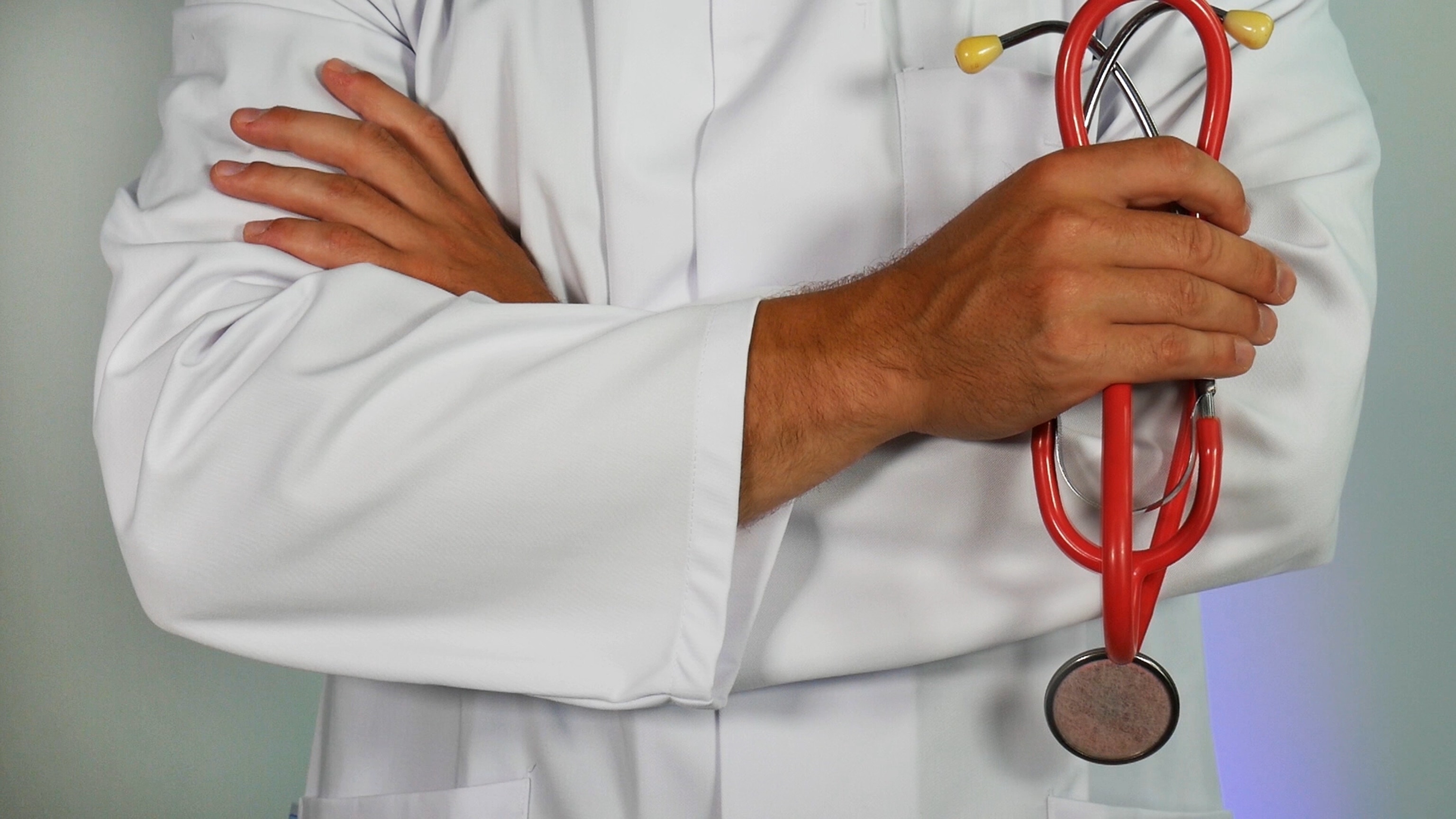 A person in medical attire with a red stethoscope in hand