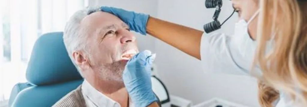 Dentist examining an older male patient’s mouth